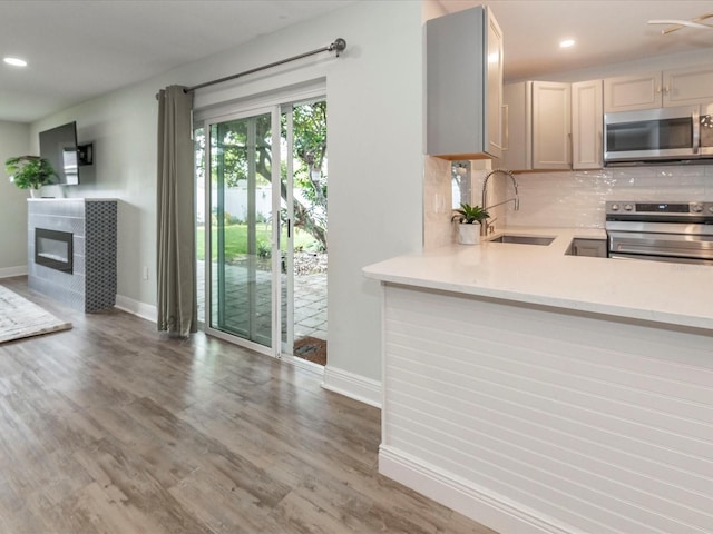 502 Duchess Dr, Lakeland, FL 33803 - kitchen featuring a sink, a glass covered fireplace, stainless steel appliances, baseboards, and tasteful backsplash