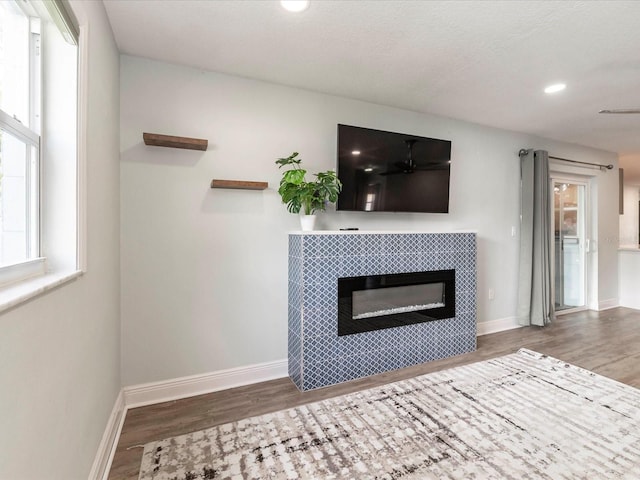 502 Duchess Dr, Lakeland, FL 33803 - unfurnished living room featuring a tiled fireplace, baseboards, and wood finished floors