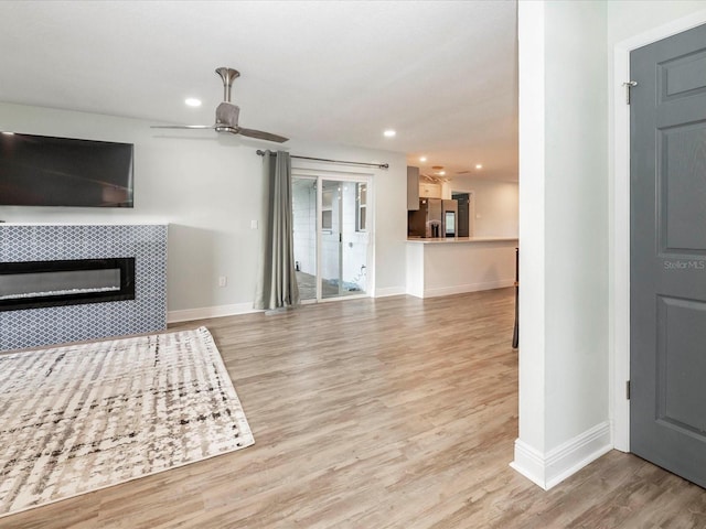 502 Duchess Dr, Lakeland, FL 33803 - unfurnished living room featuring light wood-style floors, baseboards, a ceiling fan, and a tile fireplace