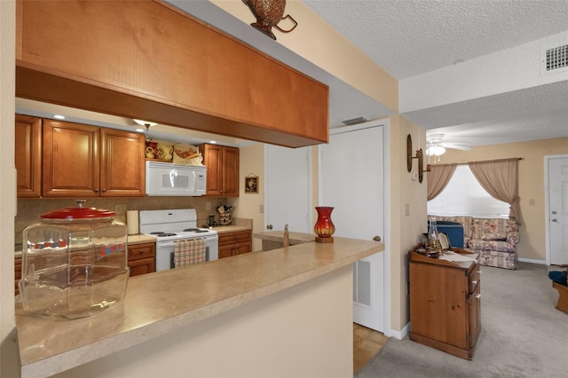 1130 N Lake Parker Ave Unit C321, Lakeland, FL 33805 - kitchen featuring white appliances, a textured ceiling, brown cabinetry, a peninsula, and a ceiling fan