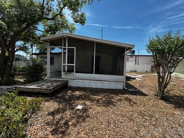 rear view of property featuring a sunroom and fence
