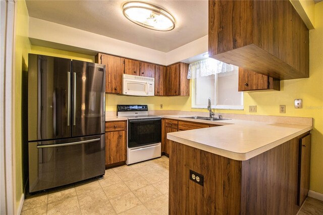 4976 Pleasant Hollow Trl, Lakeland, FL 33811 - kitchen featuring a sink, electric stove, freestanding refrigerator, a peninsula, and white microwave