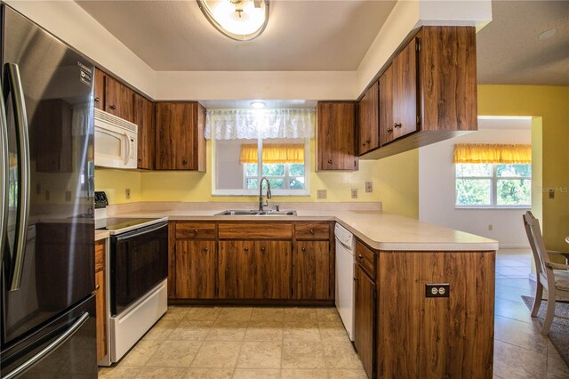 4976 Pleasant Hollow Trl, Lakeland, FL 33811 - kitchen featuring a sink, white appliances, light countertops, brown cabinetry, and a peninsula