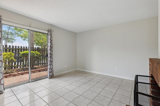 spare room featuring a textured ceiling, light tile patterned floors, and baseboards