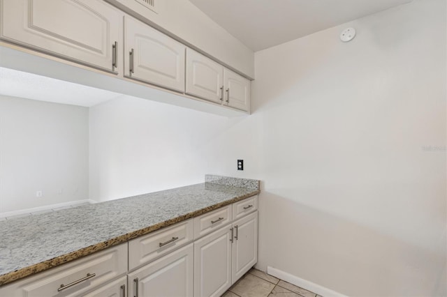 clothes washing area with baseboards and light tile patterned floors