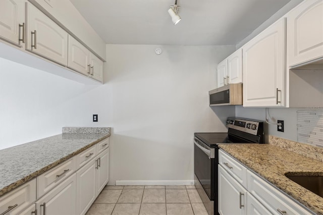 kitchen with appliances with stainless steel finishes, baseboards, white cabinetry, and light stone counters