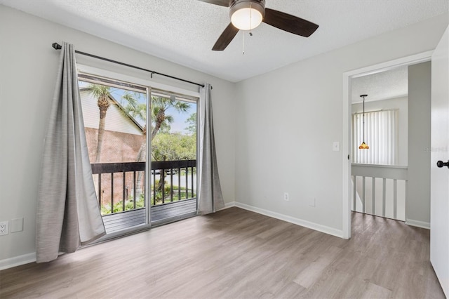 spare room featuring wood finished floors, ceiling fan, baseboards, and a textured ceiling