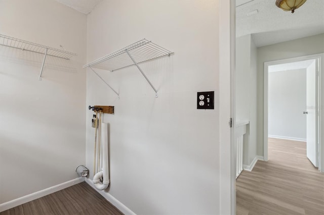 clothes washing area with baseboards and wood finished floors
