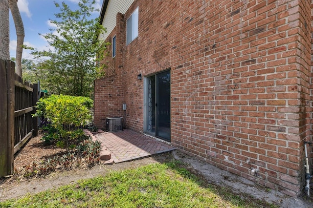 view of side of home with brick siding, a patio area, and fence