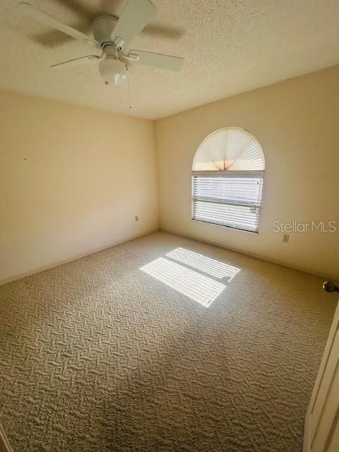 carpeted spare room with a textured ceiling and ceiling fan