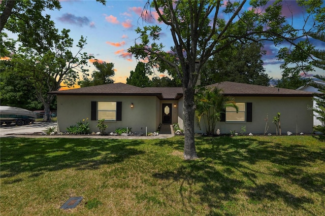 single story home with a lawn and stucco siding