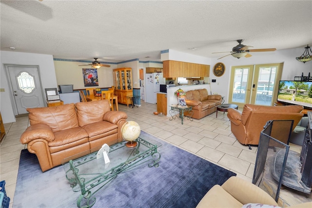 living room with a ceiling fan, a textured ceiling, light tile patterned flooring, and french doors