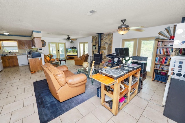 living room with a wood stove, ceiling fan, and a wealth of natural light