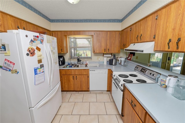 kitchen with a sink, under cabinet range hood, white appliances, and wallpapered walls