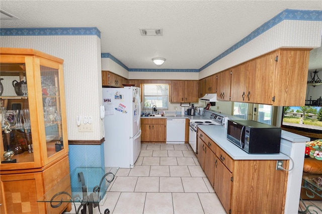 kitchen with visible vents, light countertops, under cabinet range hood, wallpapered walls, and white appliances