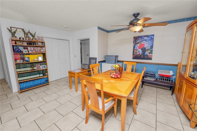 dining room featuring a textured ceiling, ceiling fan, light tile patterned floors, and wallpapered walls