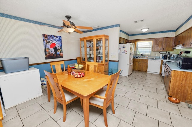 dining space with visible vents, wainscoting, ceiling fan, and wallpapered walls