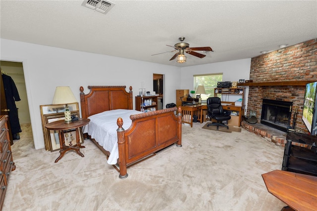bedroom featuring light carpet, a brick fireplace, a textured ceiling, and visible vents