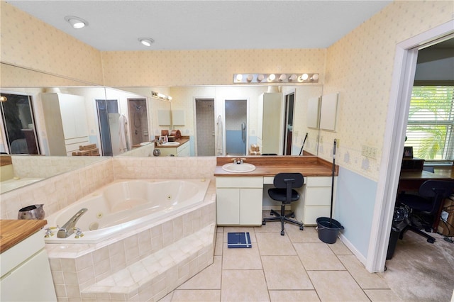 bathroom featuring wallpapered walls, a tub with jets, tile patterned floors, and vanity