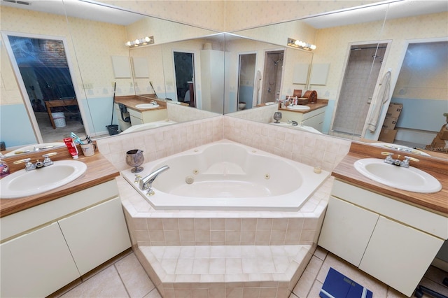 bathroom with two vanities, a tub with jets, and a sink