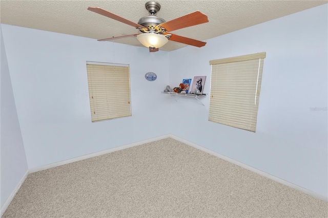 carpeted empty room with a textured ceiling, ceiling fan, and baseboards