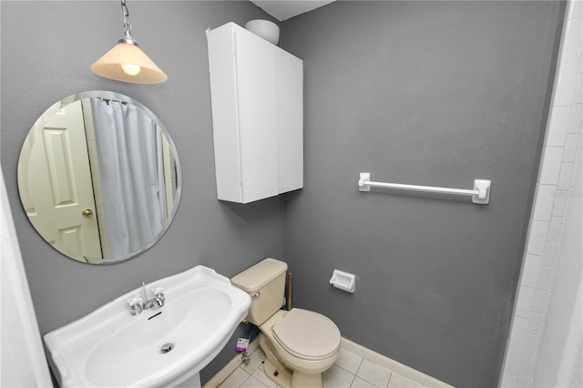 bathroom with baseboards, toilet, tile patterned floors, and a sink