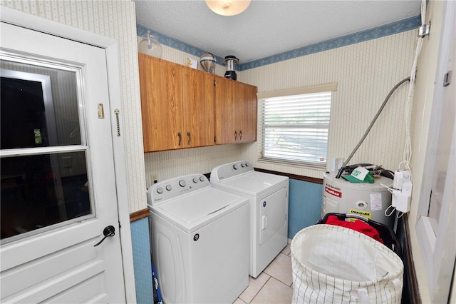 laundry room featuring wallpapered walls, washer and clothes dryer, electric water heater, cabinet space, and light tile patterned floors