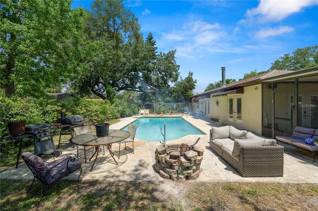 pool featuring an outdoor living space with a fire pit, a patio area, and french doors