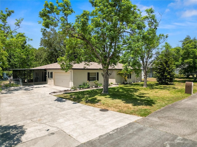 ranch-style home featuring a garage, stucco siding, a sunroom, a front yard, and driveway