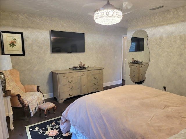 bedroom with visible vents, dark wood finished floors, baseboards, and a chandelier