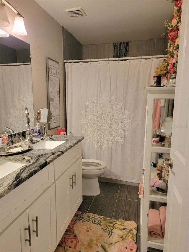 full bath with double vanity, a shower with curtain, visible vents, a sink, and toilet