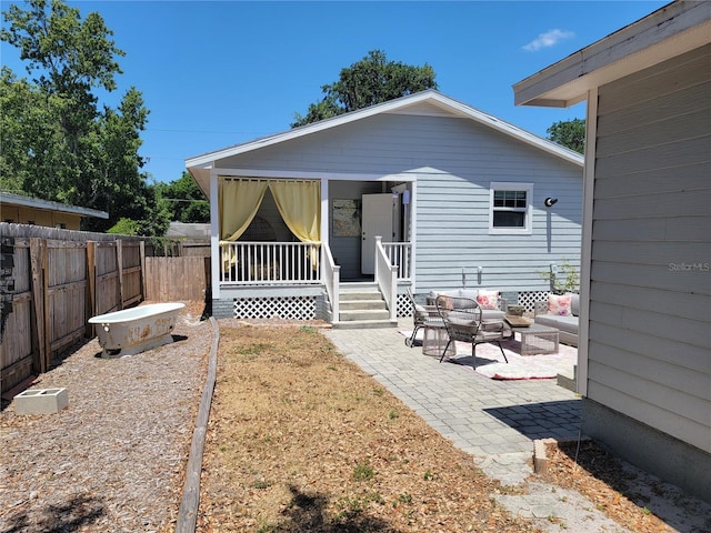 rear view of house with a patio, an outdoor living space, and fence