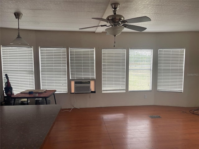 interior space with visible vents, a ceiling fan, wood finished floors, and cooling unit