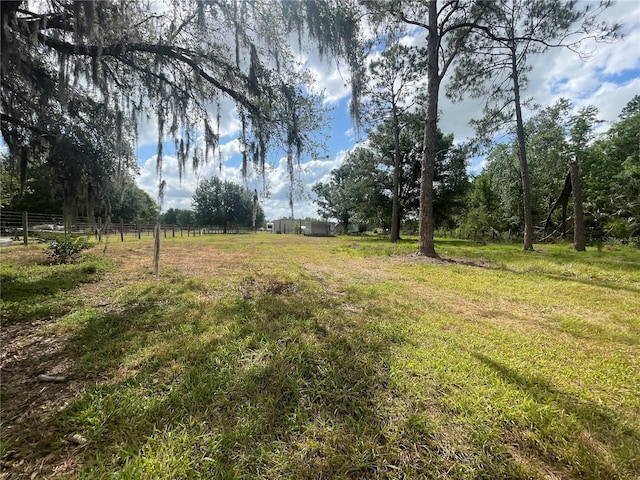 view of yard with fence and a rural view