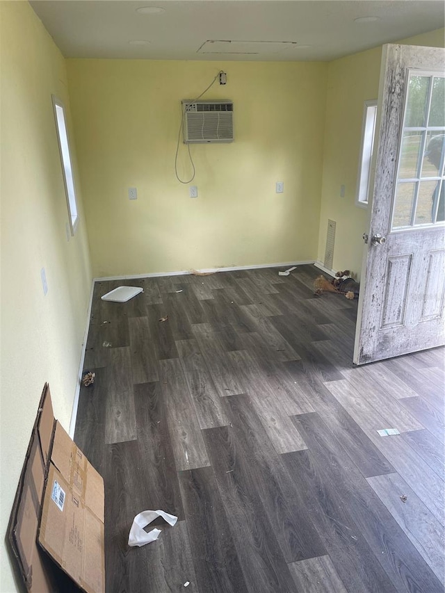 unfurnished room with baseboards, a wall mounted air conditioner, and wood finished floors