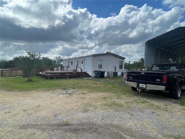 view of side of home featuring a lawn, a deck, central AC unit, a carport, and fence