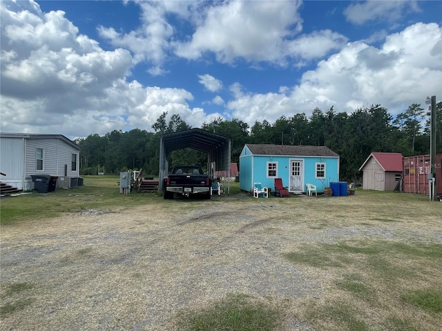 exterior space with driveway, a detached carport, and a storage unit