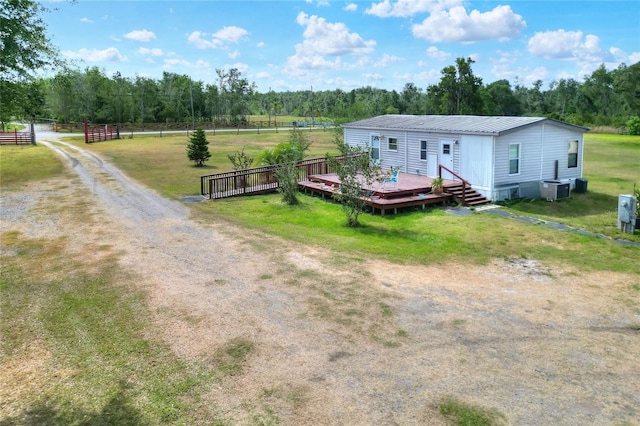 rear view of house featuring fence, a deck, central AC unit, a lawn, and metal roof