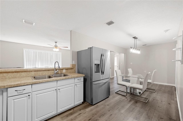 kitchen with stainless steel fridge with ice dispenser, a sink, white cabinetry, light wood-style flooring, and a ceiling fan