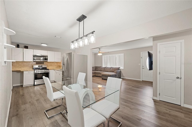 dining room with light wood-style floors, baseboards, and ceiling fan