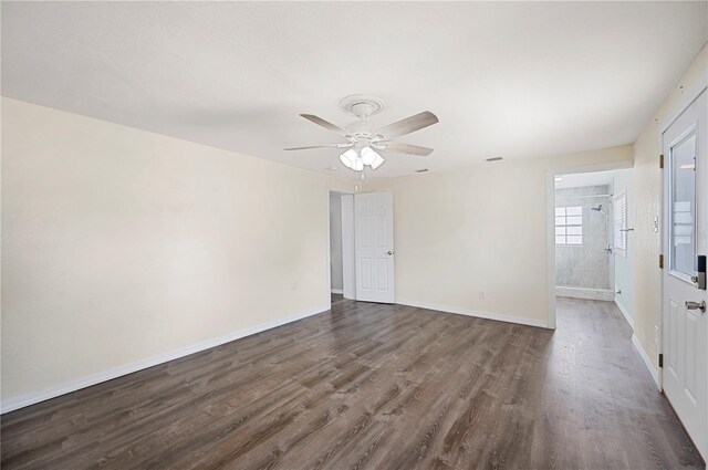 unfurnished room with dark wood finished floors, a ceiling fan, and baseboards
