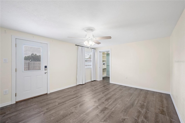 empty room with plenty of natural light, wood finished floors, baseboards, and ceiling fan