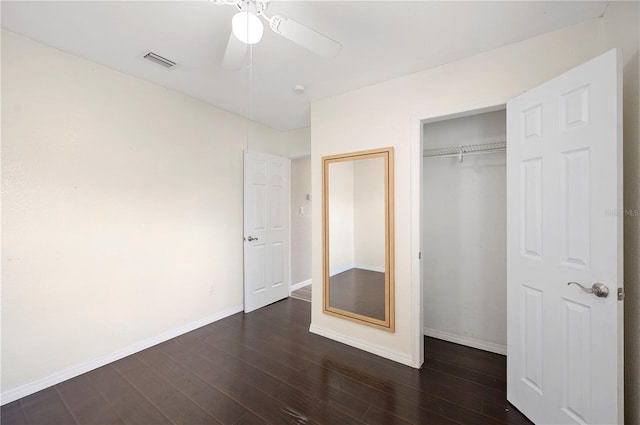 unfurnished bedroom featuring dark wood-style flooring, baseboards, a closet, and a ceiling fan