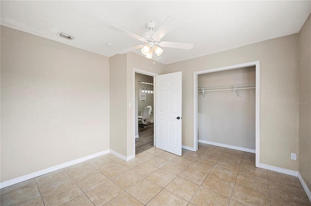 unfurnished bedroom featuring a closet, baseboards, light tile patterned floors, and ceiling fan