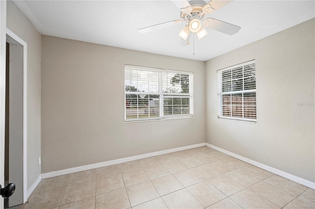 unfurnished room with light tile patterned floors, a ceiling fan, and baseboards