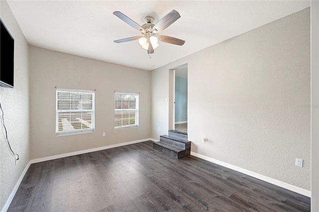 spare room with dark wood-type flooring, ceiling fan, baseboards, and a textured wall