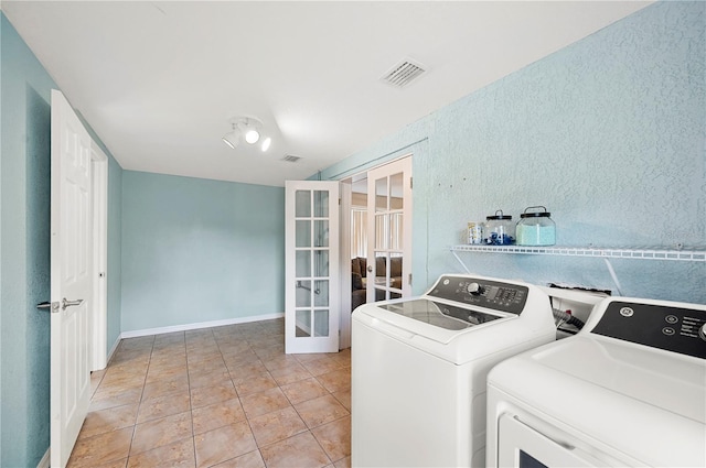 laundry area with washer and dryer, french doors, baseboards, light tile patterned floors, and a textured wall