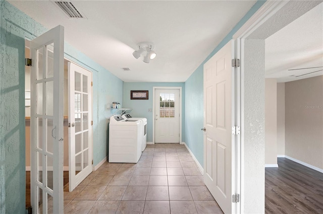 washroom featuring french doors, washing machine and clothes dryer, and baseboards