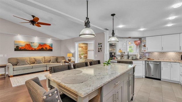 kitchen featuring stainless steel dishwasher, backsplash, a breakfast bar area, and lofted ceiling