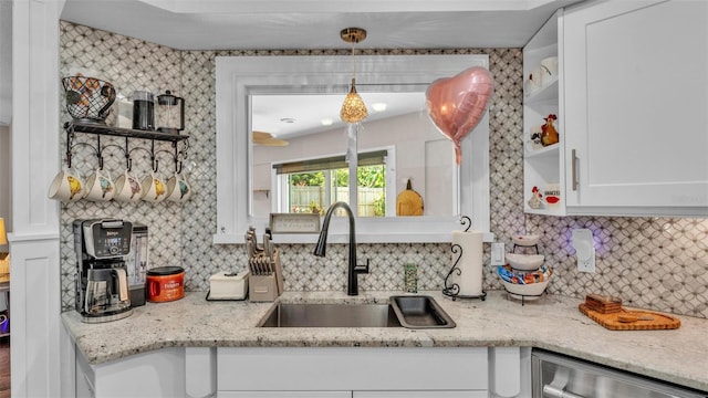 kitchen featuring decorative backsplash, open shelves, stainless steel dishwasher, a sink, and white cabinets